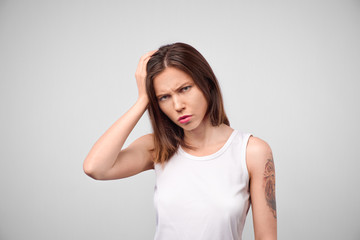 Why is that. Beautiful female half-length portrait isolated on white studio backgroud. Young emotional sad, frustrated and bewildered woman. Human emotions, facial expression concept