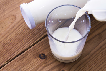 bottle with milk and glass of milk on wooden table