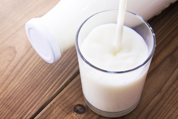 bottle with milk and glass of milk on wooden table