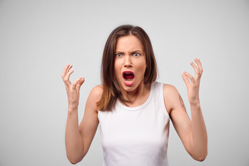 Angry woman looking at camera. Aggressive business woman standing isolated on white studio...