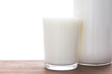 bottle with milk and glass of milk on wooden table