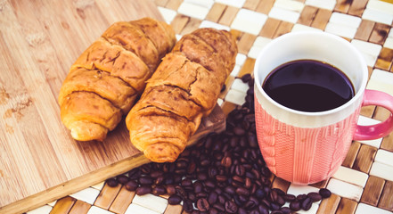 cup of coffee and croissants on wooden background