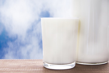 bottle with milk and glass of milk on wooden table