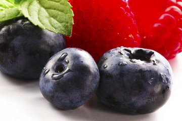 Close-up arrangement mixed, assorted berries including blackberries, strawberry, blueberry, raspberries and fresh leaf on white