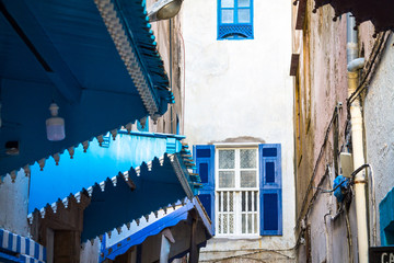 Open window with blue shutters shutters against a white wall