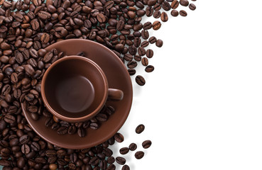 Ceramic Cup and saucer stands on scattered coffee beans isolated on white