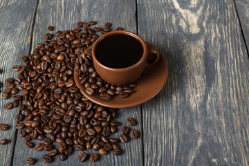 Coffee in ceramic Cup, coffee beans scattered near, on wooden table