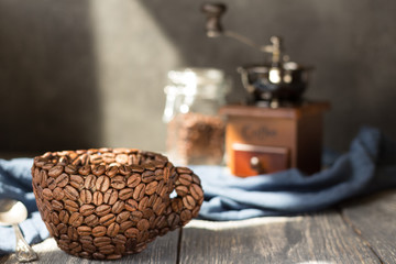 Cup made of coffee beans, standing on gray wooden table