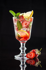 Red cocktail with strawberry, ice, mint, lemon