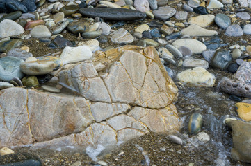 Naklejka na ściany i meble pebble stones on the sea beach, the rolling waves of the sea with foam