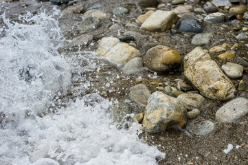 Naklejka na ściany i meble pebble stones on the sea beach, the rolling waves of the sea with foam