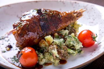 Tasty turkey leg in sauce with pounded mashed potatoes and tomatoes on a plate. Turkey with garnish