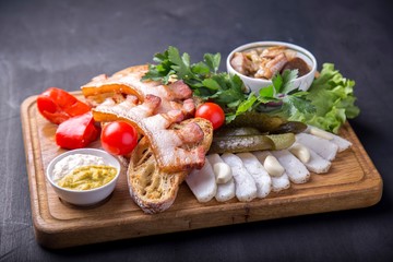Fried brisket with fried pieces of bread,  cut lard, fresh tomatoes and marinated mushrooms. Tasty appetizer on wooden board