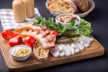 Snack with fried brisket, bread,  cut lard, fresh tomatoes and marinated mushrooms. Tasty appetizer on wooden board