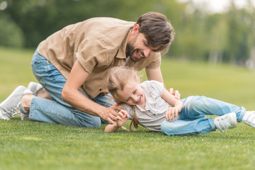 Fototapeta na wymiar happy father and daughter having fun together on green lawn in park