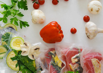 Fillet and vagatables in vacuum bags for sous vide coocing on white marbleized background
