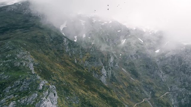 Epic arial view of high mountain scenery with black birds circling in the air