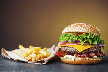 big cheeseburger with heap of french fries on slate board - obrazy, fototapety, plakaty