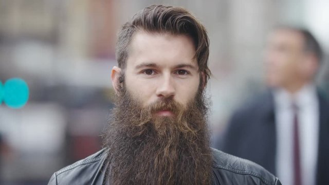 Portrait of serious looking bearded male in the city, in slow motion