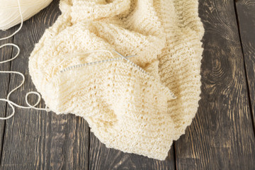 Knitted product of light soft yarn handmade, and knitting needles, on table