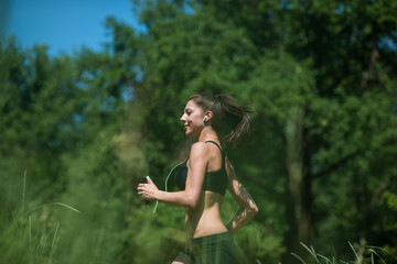 Naklejka na ściany i meble Young woman running in the woods. The girl is engaged in sports.
