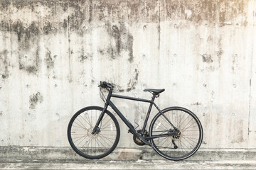 Fototapeta na wymiar Matt black race road bike parked in front of grunge textured background with vintage tone. 
