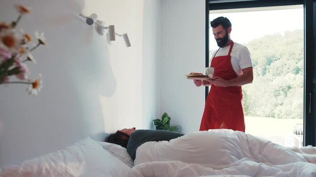 Good-looking bearded paramour serves breakfast in bed to his beloved woman. Happiness, feeling good, romantic morning. True feelings, couple goals, dating.