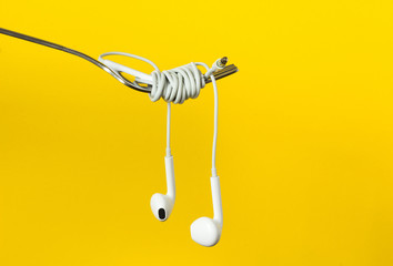 Fork and headphones on a yellow background, close-up