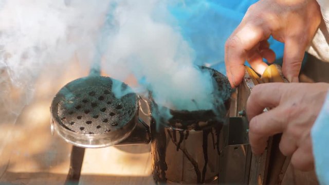 bee-maker of a smoke pipe beeper smoker device for repelling evil bees. slow motion video apiary. beekeeping lifestyle concept bee agriculture