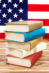 Stack of books on the table against american flag. American education.