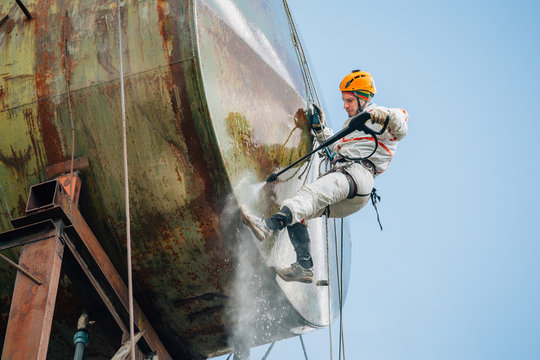 Industrial Climber Washing Big Barrel With Water Pressure. Risky Job.