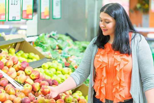 Shopping concept. Woman taking apple in the supermarket store.