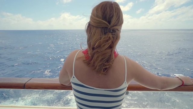 Woman stands on balcony of cruise ship. Girl look around on cruise liner