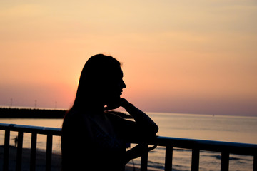 Fototapeta premium Silhouette of a beautiful girl at sea in the setting sun