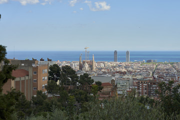 Overview of Barcelona in Spain, highlighting the Cathedral of the Sagrada Familia, designed by the architect Gaudi, still under construction and two large skyscrapers next to the Mediterranean Sea