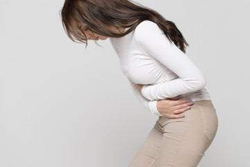 Health issues problems concept.Woman suffering from stomach pain, feeling abdominal pain or cramps, side view.Period menstruation, female health problem, aching belly and gynecology - obrazy, fototapety, plakaty