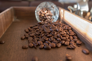 Coffee beans spilling out of a coffee glass. Timber surface,