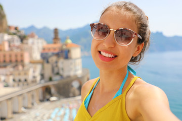 Self portrait of young smiling woman with sunglasses in Atrani village, Amalfi Coast, Italy. Selfie photo of girl in her summer holidays in Southern Italy.