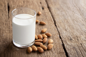 Almonds and a glass of milk on the wooden table.