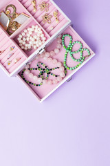 Open jewelry box with neclaces, earrings and rings on pastel background. Top view