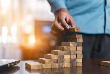 Hand of businessman pulling wooden block before fail on building tower at home and drape change,...
