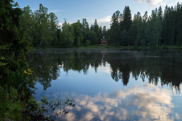 Beautiful view of a pavilion, small and misty lake and forest at the Aulanko nature reserve in Hämeenlinna, Finland, at morning in the summer.