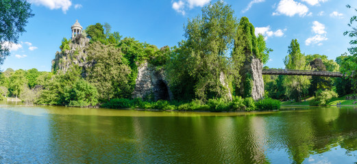 Panoramic view of the park of Buttes-Chaumont in summer including the suspension bridge that faces...