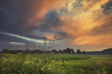 Fototapeta na wymiar Dramatic Sunset Clouds over Green Countryside Fields
