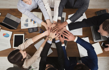 Team of united coworkers standing with hands together