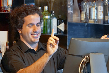 Registration male of bartender employee of a new order by a cash register. The barman pays the order with a credit card. Service concept