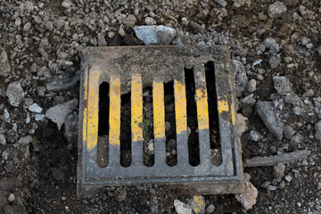 Old metal street manhole cover painted with yellow paint. Road reconstruction. Sewer hatch.