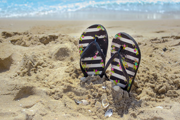 Flip flops in the sand against the background of the sea.