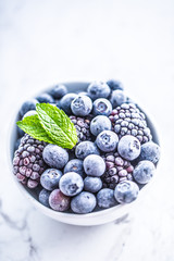 Close-up frozen blueberries and blackberries with mint leaves