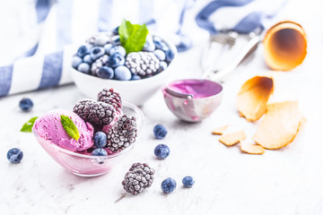 Obraz na płótnie Canvas Blueberry and blackberry ice cream in bowl with frozen fruits